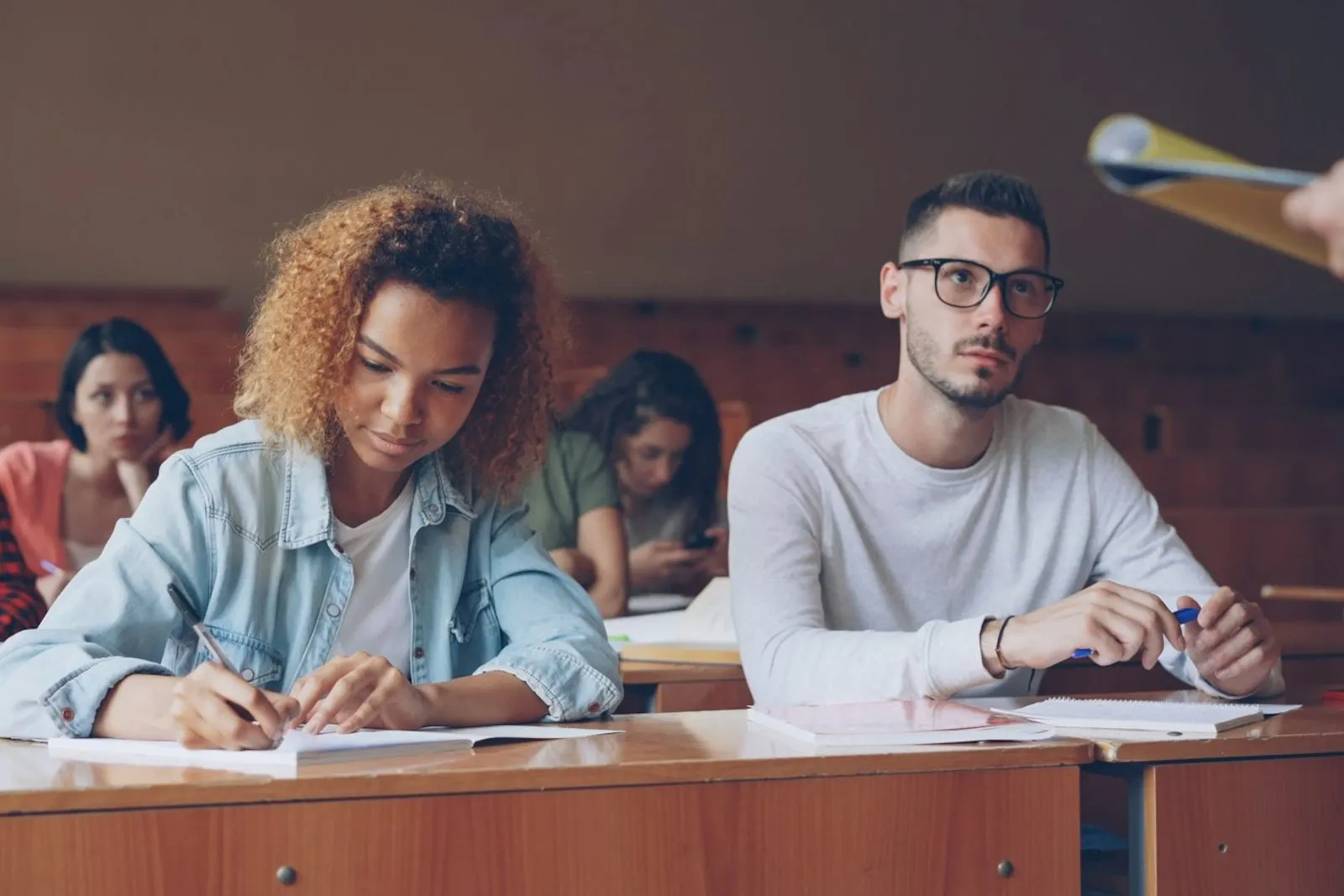Alumnos escribiendo en sus carpetas durante la clase